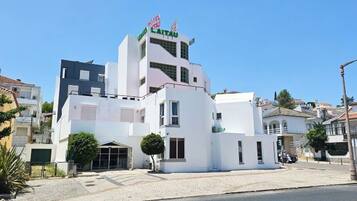 Un hotel moderno con facciata bianca, un cartello ben visibile e una bandiera.