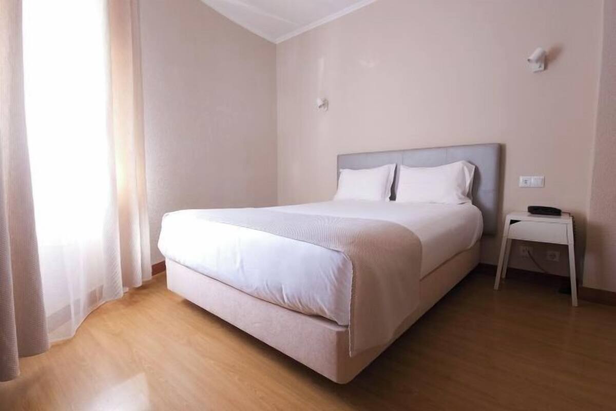 A neatly arranged bedroom with a large bed, a bedside table, and a nightstand.