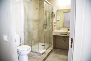 Une salle de bain avec une douche à parois de verre, des toilettes et un lavabo avec un miroir.