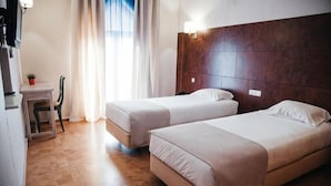 A hotel room with two beds, a desk, and a chair. - Hotel Laitau (Nossa Senhora da Anunciada)