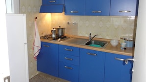 A kitchen with blue cabinets, a white refrigerator, a gas stove, and a sink.