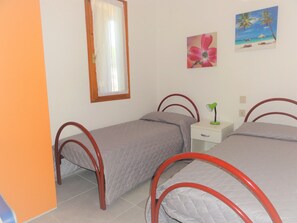 Ein Schlafzimmer mit zwei Einzelbetten, einem Nachttisch, einem Spiegel und einem Wandbild.