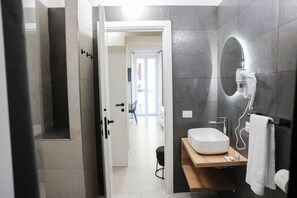 A modern bathroom with a large mirror, a white sink, and a towel rack.