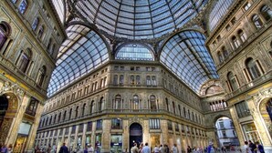 A spacious, ornate train station with a large glass roof and multiple arches.