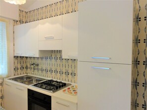 A kitchen with white cabinets, a gas stove, and patterned backsplash tiles. - Apartment in Villa With Fenced Garden (San Michele al Tagliamento)