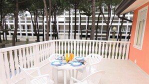A balcony with a white railing, a round table with white chairs, and a view of a building with multiple windows. - Apartment in Villa With Fenced Garden (San Michele al Tagliamento)