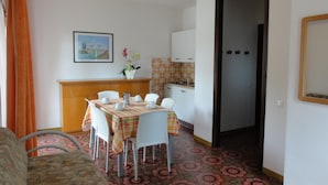 A compact living space with a dining area, kitchenette, and a door leading to another room. - Apartment in a Villa With Balcony (San Michele al Tagliamento)