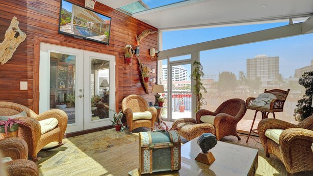 A spacious room with wicker furniture, a large window, and a view of the city.