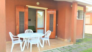 Un patio con una mesa y sillas, una puerta corrediza y un ventanal pequeño.