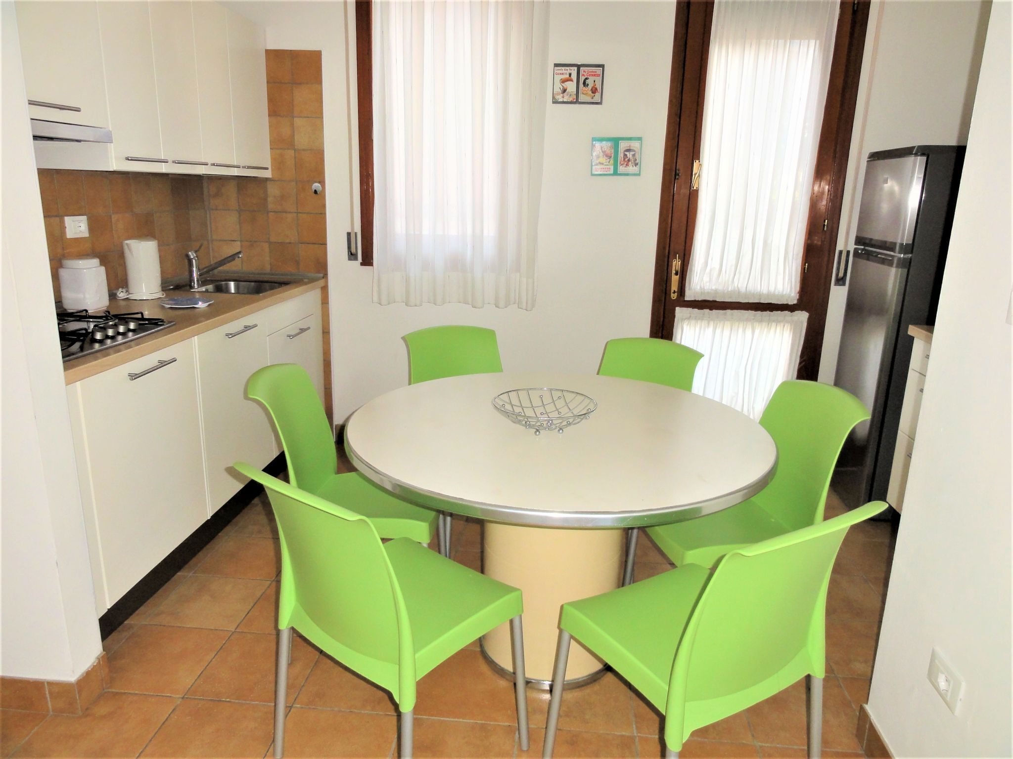 Eine kleine Küche mit Esstisch und vier Stühlen, inklusive Kühlschrank und Herd.