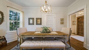 A dining room with a wooden table, cushioned bench, and a chandelier.