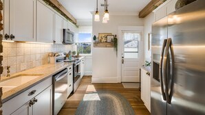A kitchen with white cabinets, a stainless steel refrigerator, and a wooden floor.