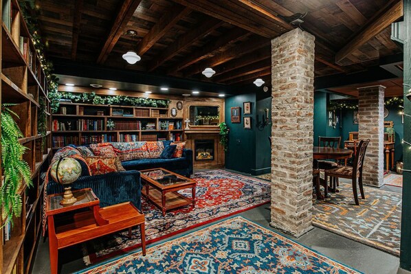 A cozy library with bookshelves, a blue sofa, and a fireplace.