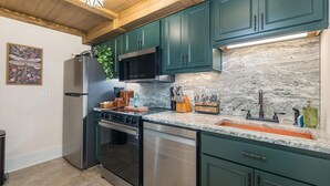 Cozinha com armários verde-água, eletrodomésticos de aço inoxidável, bancada de granito e luminária em formato de estrela.