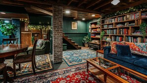 Uma sala de estar acolhedora com teto de madeira, uma estante de livros, um sofá e um espaço de refeições.