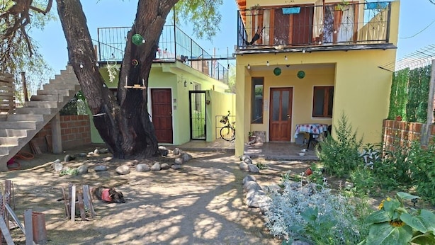Ein zweistöckiges Gebäude mit Balkon, Treppe und Gartenbereich mit Steinen und Pflanzen.