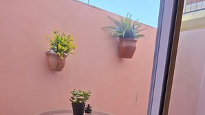 Ein kleiner Glastisch mit einem Blumentopf, platziert vor einer rosafarbenen Wand.