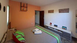 Ein Schlafzimmer mit einem Bett, einer Bank, einem Regal und einer Tür.