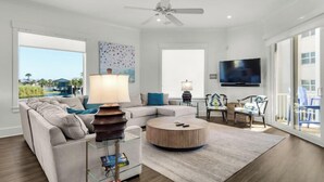 Un salon moderne avec un canapé d’angle, une table basse ronde et un ventilateur de plafond.