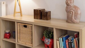 Een houten console tafel met een lamp, een lijstwerk, een katbeeldje en boeken.