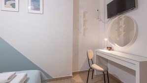 Een moderne badkamer met een wit wastafelmeubel, een ronde spiegel en een wandgemonteerde televisie.