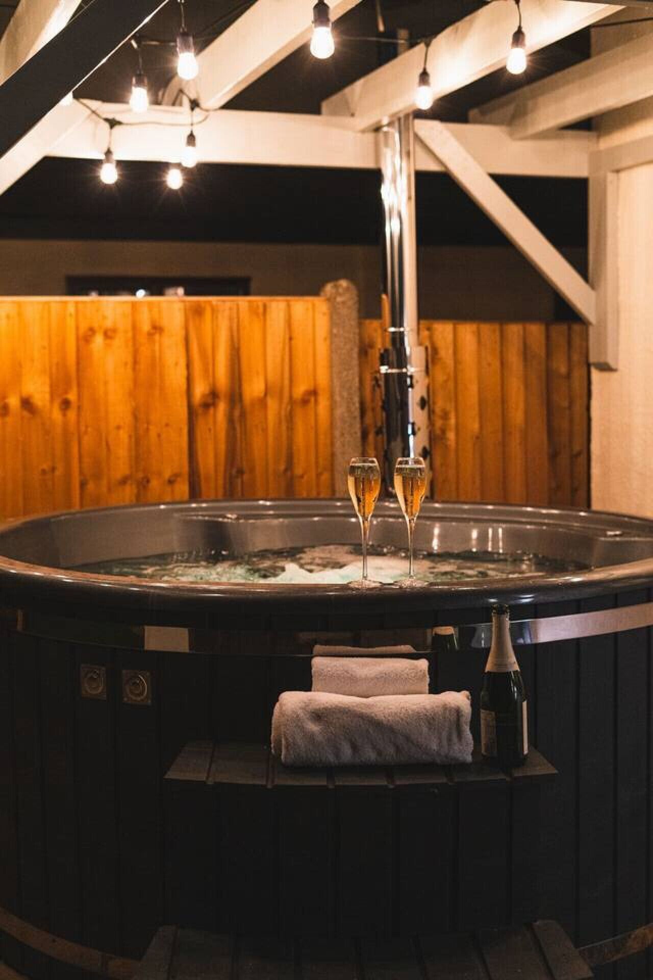 A hot tub with two glasses of champagne, a towel, and a bottle of champagne.