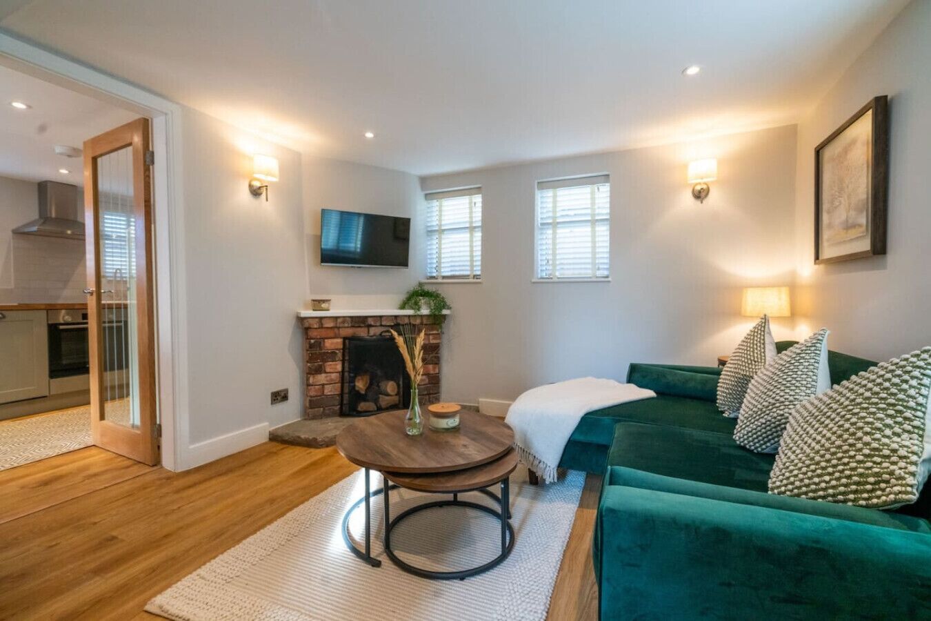 Un salon chaleureux avec un canapé vert, une cheminée et un téléviseur fixé au mur.