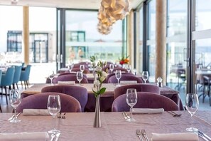 A restaurant with tables set for dining, a view of the sea, and a modern interior design. - Hotel Plaža Duće (Duce)