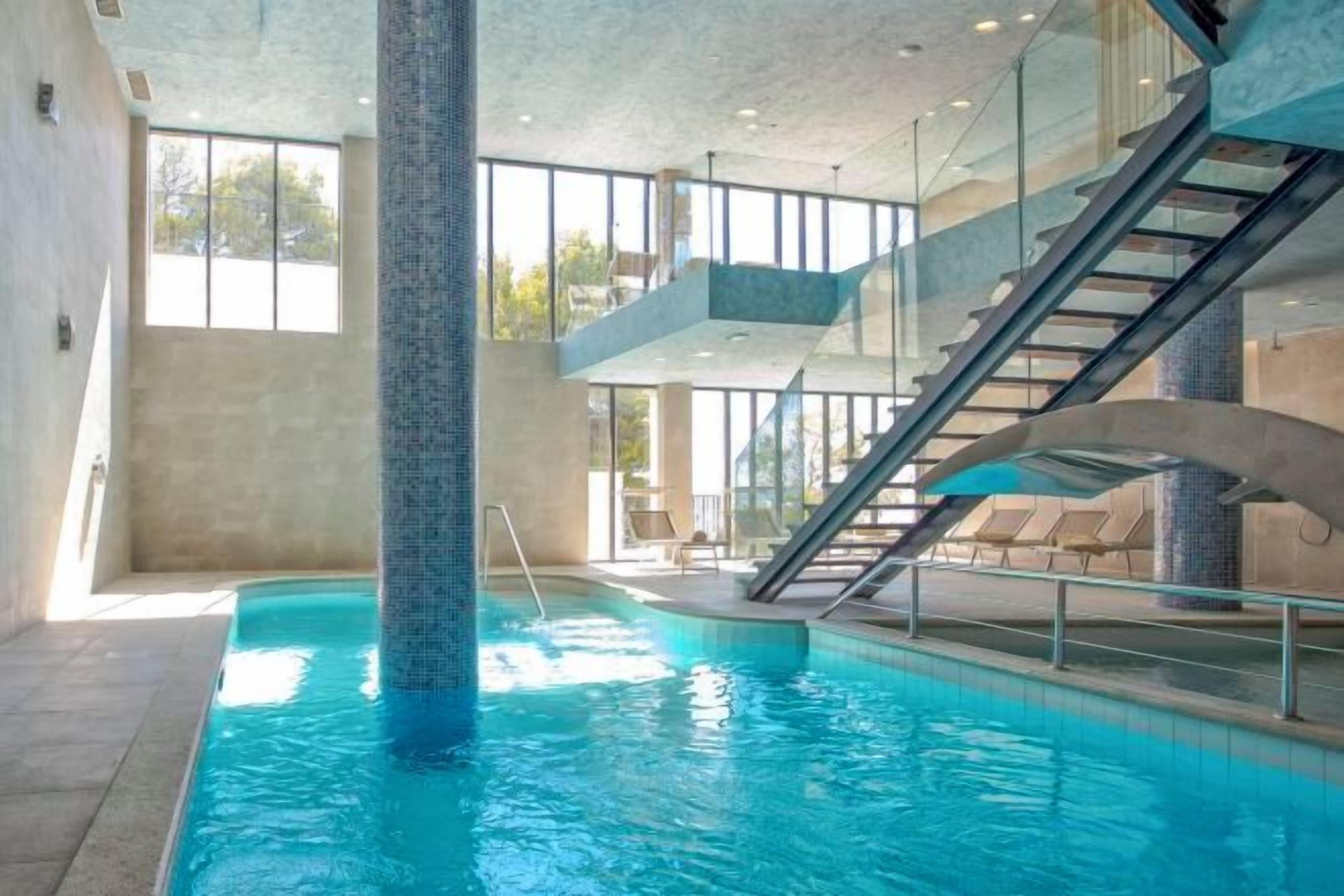 Una piscina interior con vistas despejadas a las escaleras que conducen a un balcón.