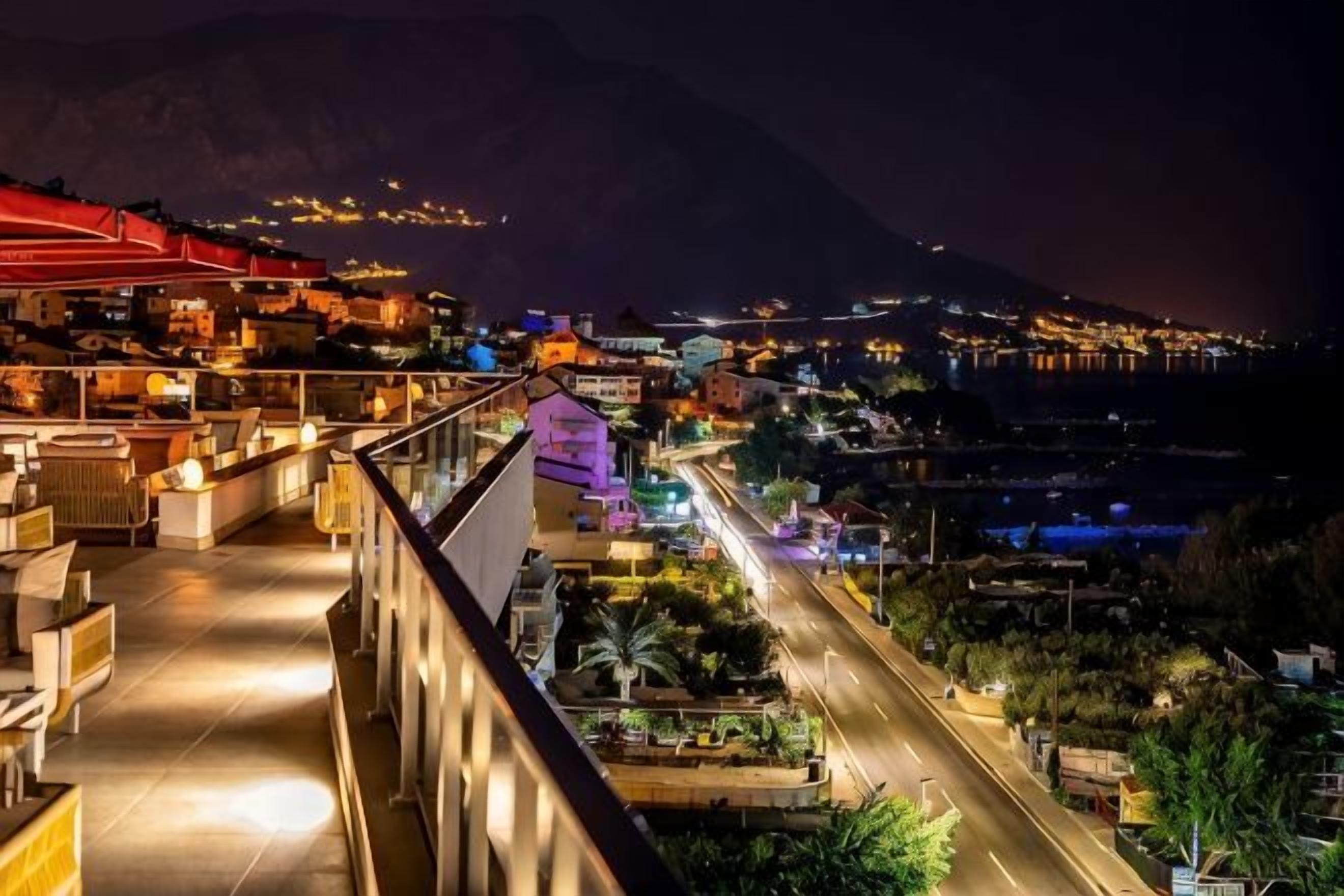 A hotel with a balcony overlooking a cityscape at night.
