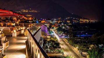 A hotel with a balcony overlooking a cityscape at night.