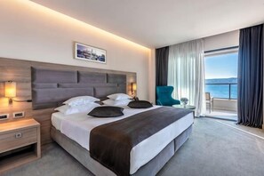A hotel room with a large bed, bedside tables, a chair, and a view of the sea. - Hotel Plaža Duće (Duce)