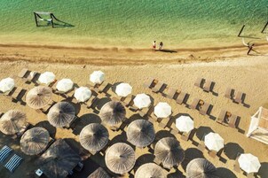 Vista aérea de una playa con hileras de sombrillas y sillas de playa, algunas con texto.