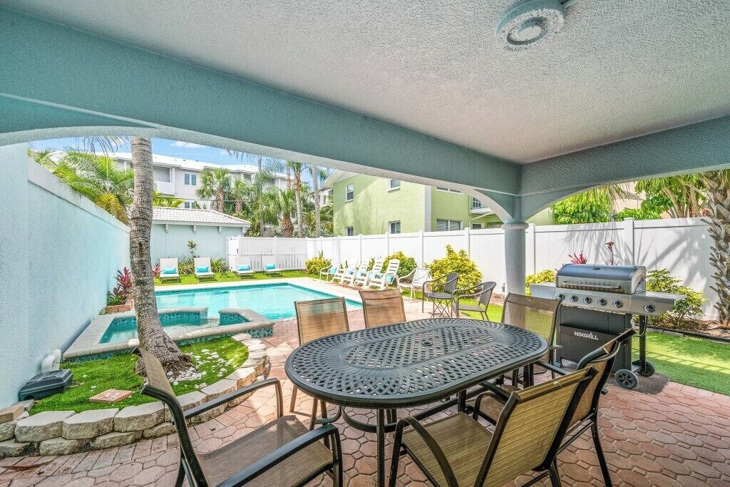A covered patio with a pool, a grill, and outdoor seating.