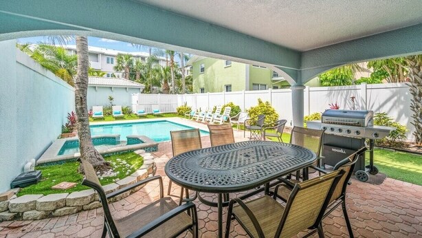 A covered patio with a pool, a grill, and outdoor seating. - Apres Sea at Cinco Siesta (Siesta Key)