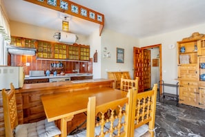 A traditional kitchen with wooden cabinets, a large wooden table, and a dining area.