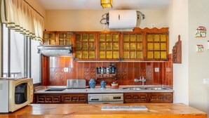 Una cocina con armarios de madera, horno empotrado, microondas y un lavabo.