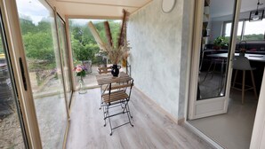 A room with a dining table, chairs, a vase with dried plants, and a view of greenery outside. - Gîte 'Gite Villarnoux' with Private Terrace, Wi-Fi and Air Conditioning (Bussières)