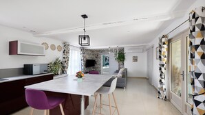 A modern kitchen with a central island, a dining area with chairs, a sofa, and a TV. - Gîte 'Gite Villarnoux' with Private Terrace, Wi-Fi and Air Conditioning (Bussières)