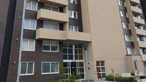 A multi-story residential building with balconies, a ground-level entrance, and a small landscaped area with plants. - Fully equipped apartment, bedroom en suite in Valdivia, direct access to the city entrance. (Valdivia)