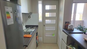 A compact kitchen with a refrigerator, stove, and a window. - Fully equipped apartment, bedroom en suite in Valdivia, direct access to the city entrance. (Valdivia)