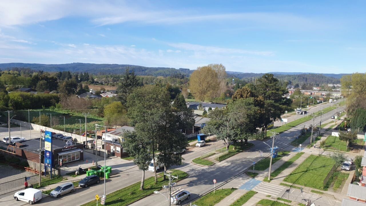 Une zone commerciale comprenant une station-service, un parking et une route où circulent des véhicules.
