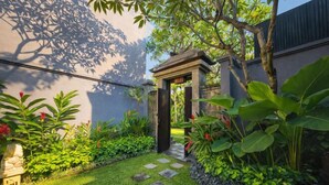 A garden pathway leading to a stone archway, surrounded by lush greenery and a stone wall. - Seminyak Icon Villa & Spa (Bali)