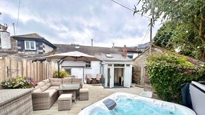 A backyard with a hot tub, outdoor seating, and a small shed. - Pilgrim Cottage - sleeps 4 guests  in 2 bedrooms (Newquay)