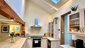 A modern kitchen with wooden cabinetry, a built-in oven, and a skylight. - Pilgrim Cottage - sleeps 4 guests  in 2 bedrooms (Newquay)
