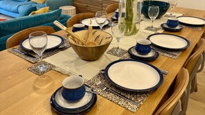 A dining table set with blue and white plates, a wooden bowl, and a vase with sunflowers.