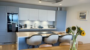 A modern kitchen with white cabinets, a built-in oven, and a dining area with a wooden table and chairs.