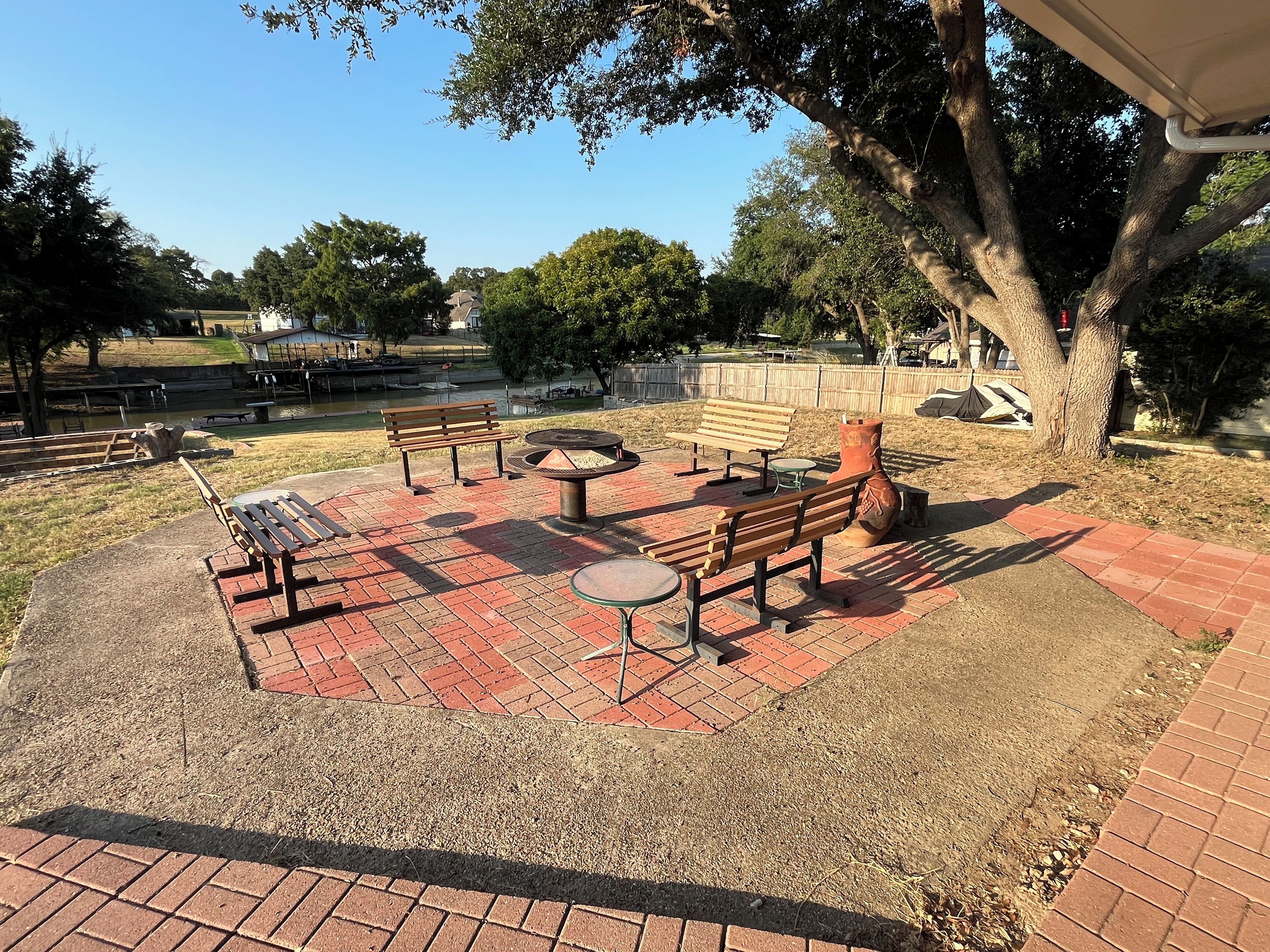 An outdoor patio area with brick flooring, wooden benches, and tables.