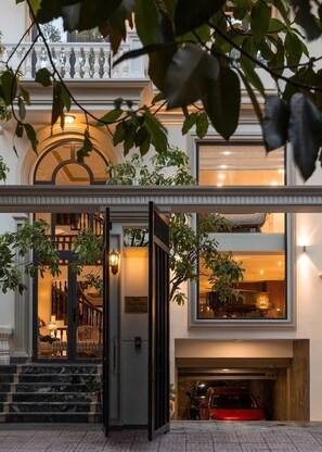A hotel entrance with a grand staircase, a reception area, and a visible car in the parking garage. - Villa Harmony 9 bedrooms (Ho Chi Minh City)