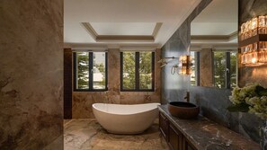 Un bagno moderno con una vasca da bagno indipendente, ampie finestre e un pavimento in marmo.